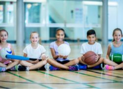 Children sitting on gym floor waiting to play games